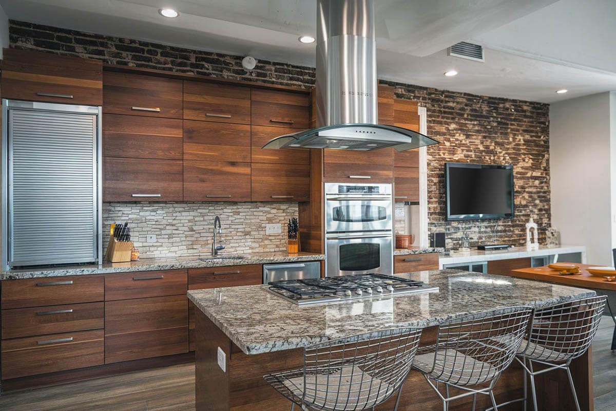 Kitchen with brick wall, granite island with built in stove