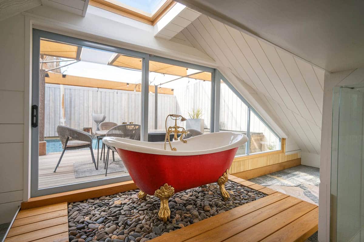 Bathroom with red acrylic bathtub and view to backyard