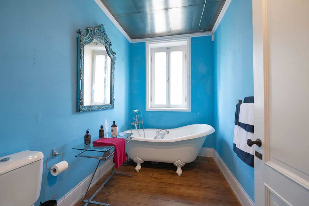 Bathroom with blue patterned wallpaper and wrought iron candle style chandelier