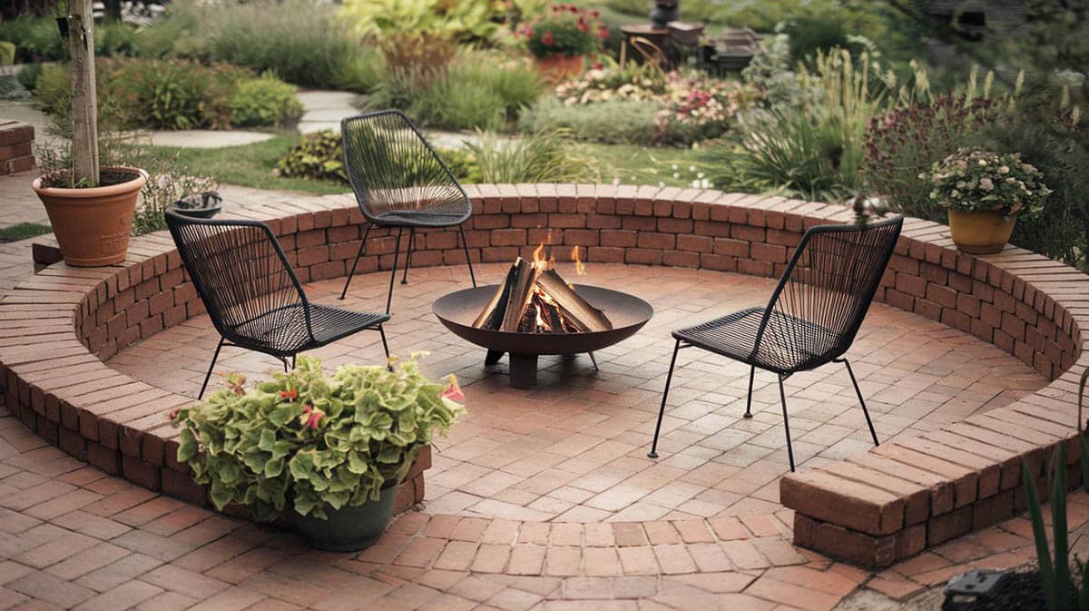 Round brick fire pit patio with concrete step path through garden