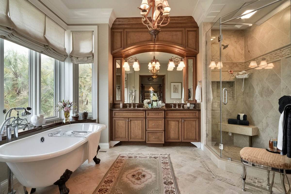 Bathroom with floor to ceiling glass shower partition, white chair and natural stone flooring