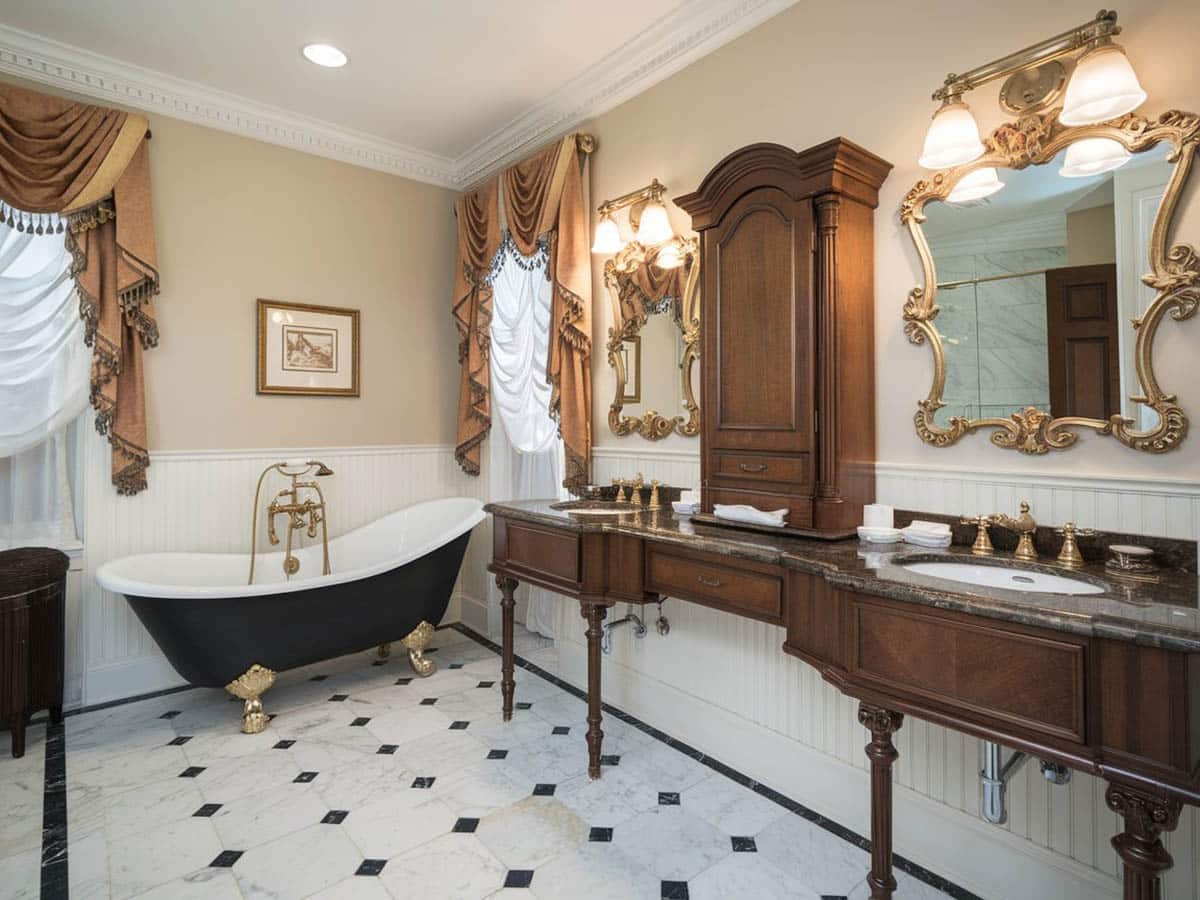 Bathroom with black tub with gold lion feet, table top cabinet and curtains