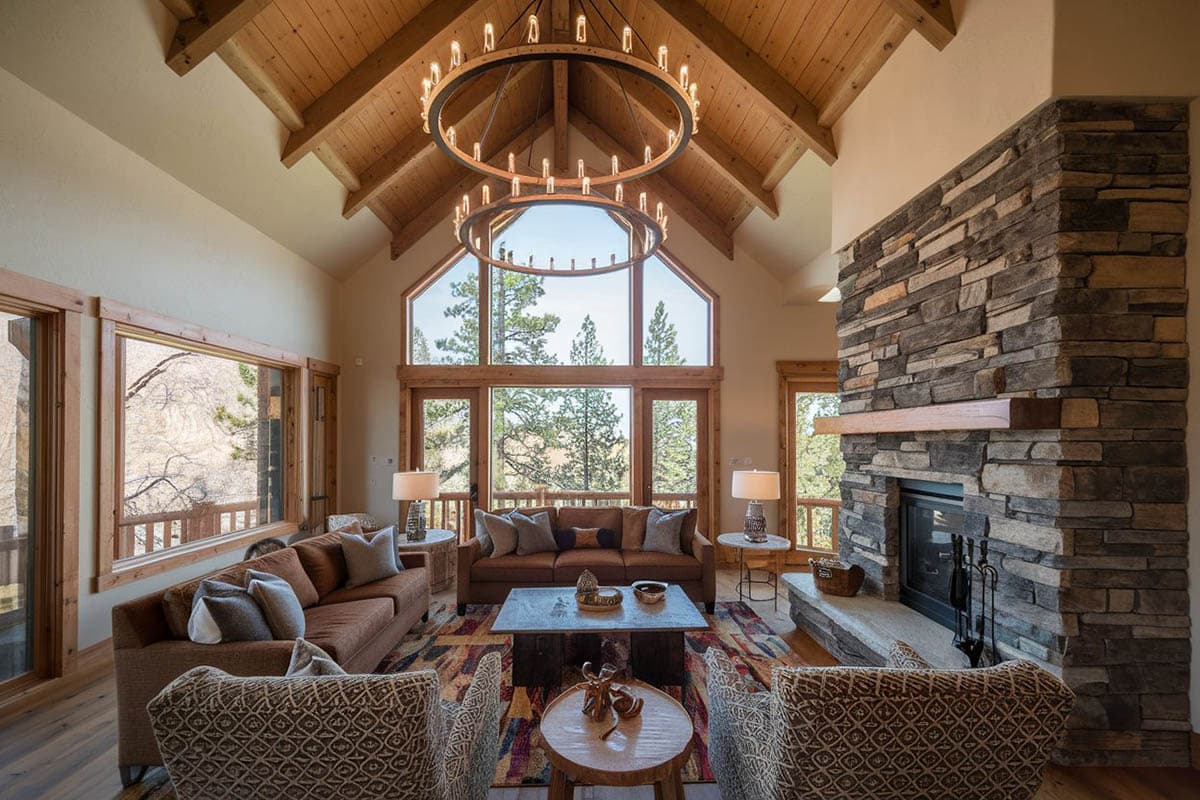 Alpine room with large stone fireplace, wood flooring and French windows