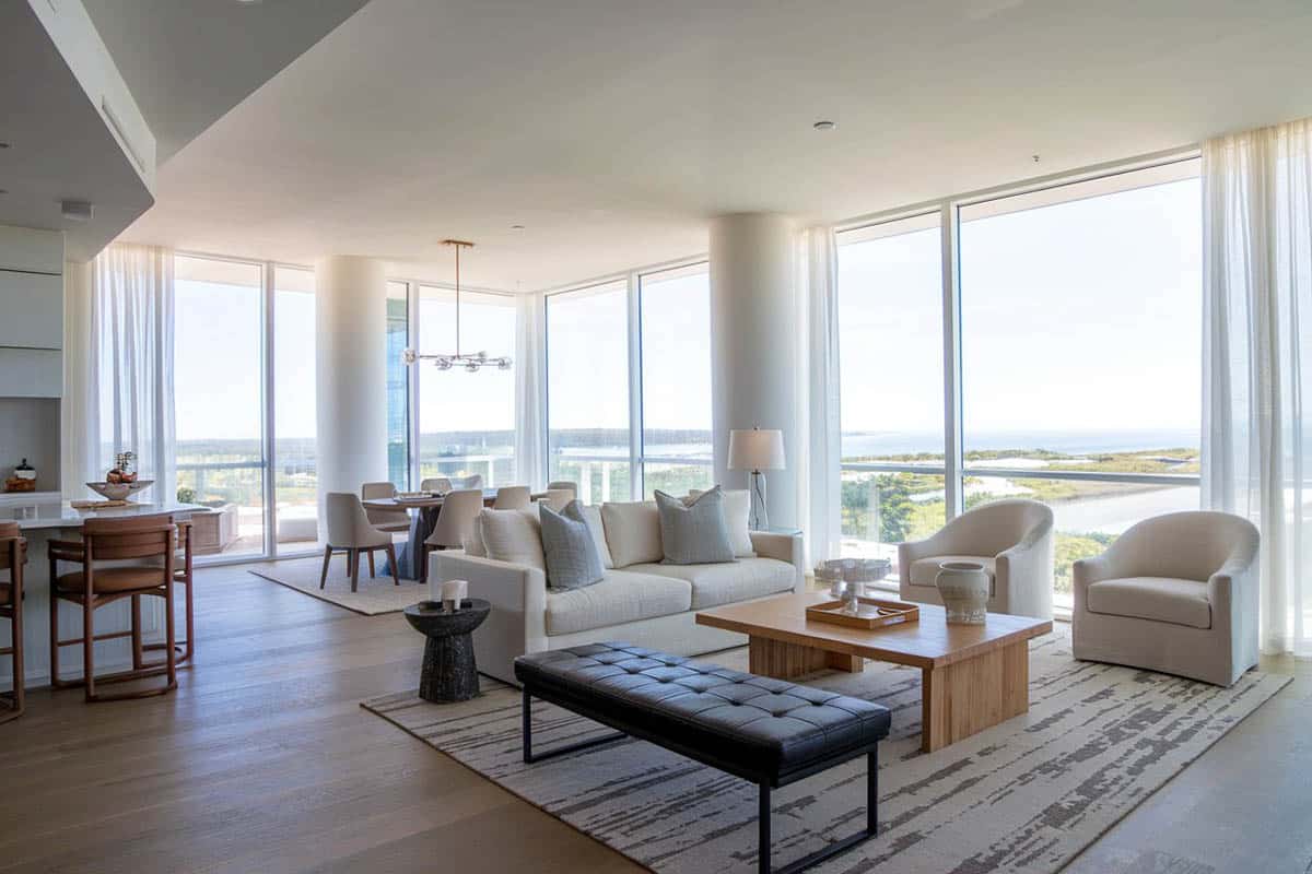 Room with muted color theme and wraparound window s with views of waterfront