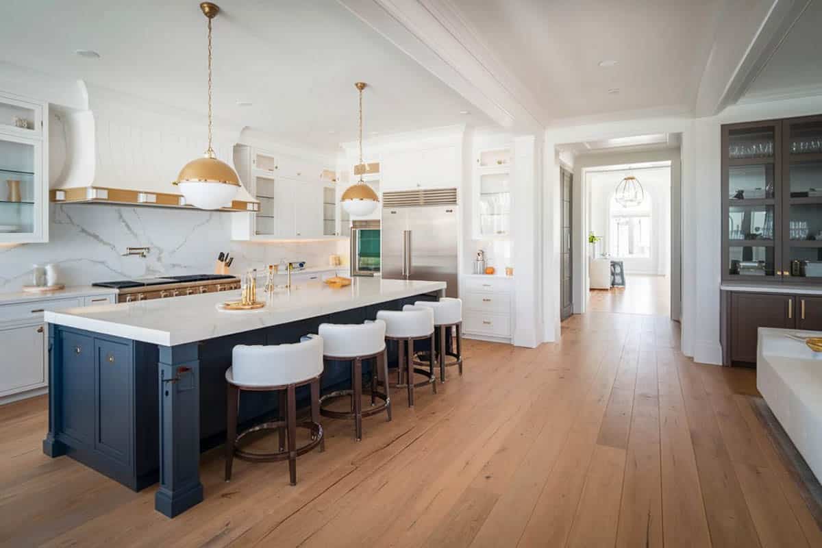 Beautifull kitchen with calacatta stone marble countertop island, hand rubbed antique brass pendant hanging lighting and hickory wood floors