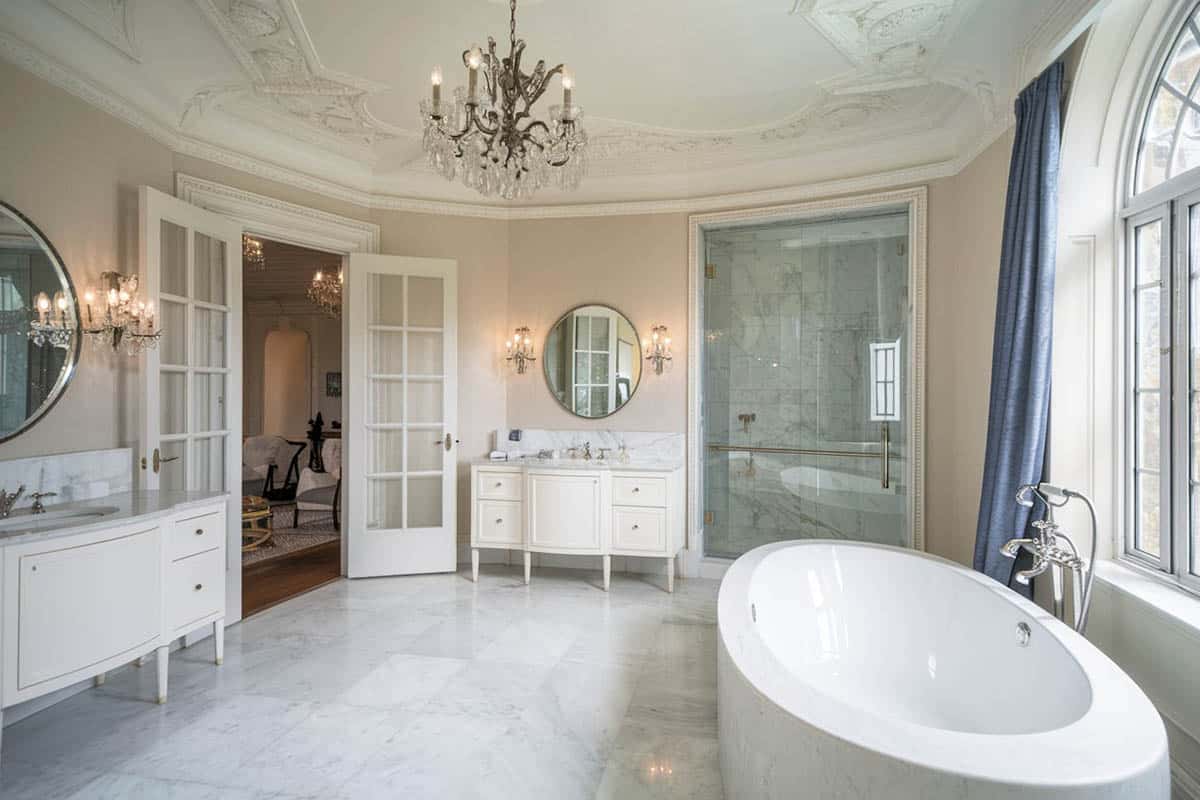 Luxury white bathroom with marble floors and tub enclosure with chandelier
