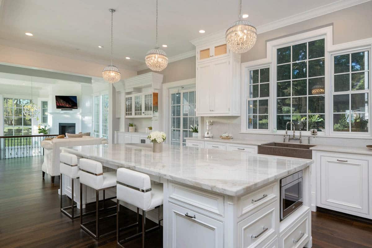 White contemporary style kitchen with sugar beige marble counters and globe pendant lighting