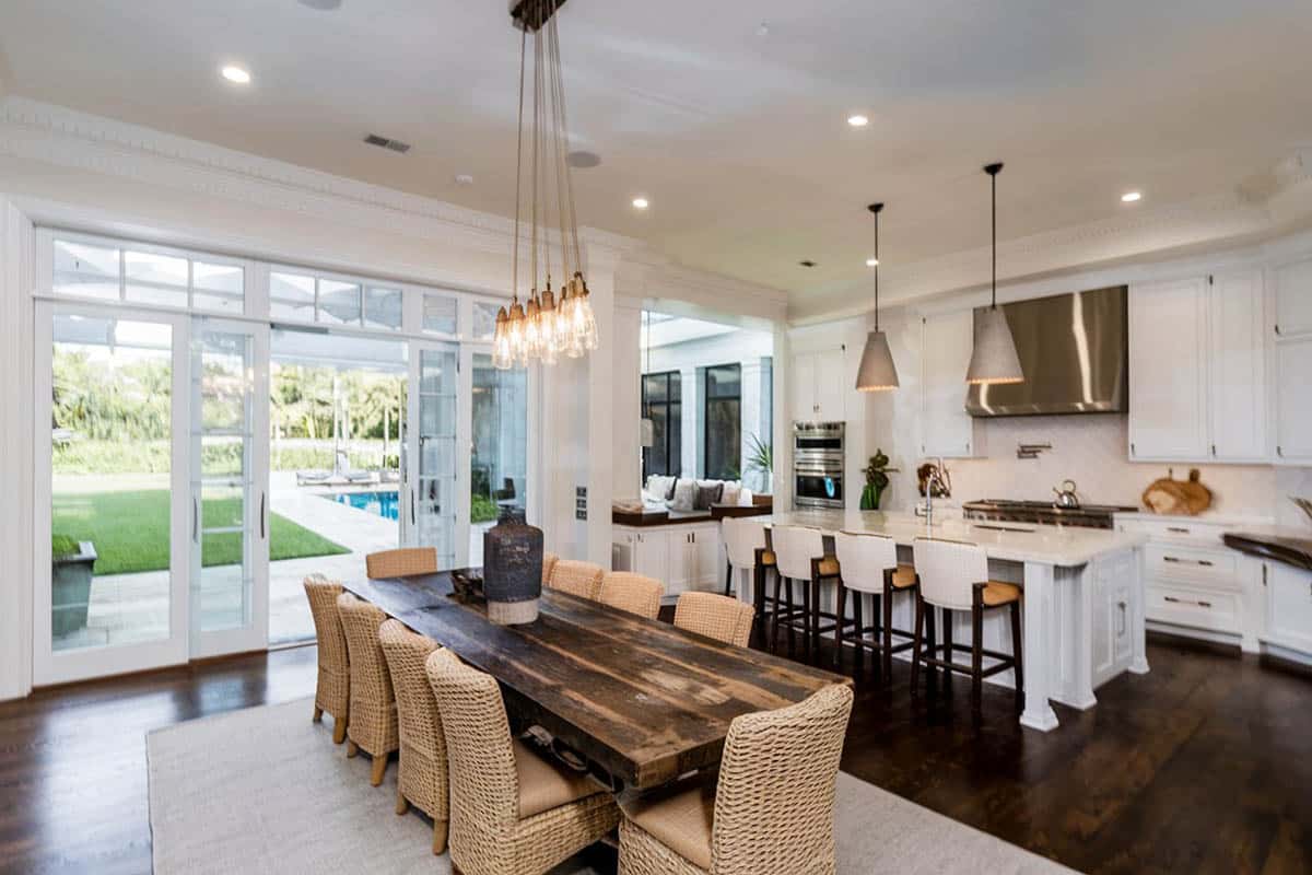 Open plan contemporary kitchen with island, gray quartz countertops and rustic wood dining table