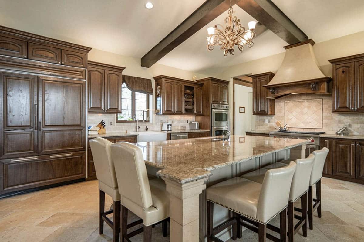 Kitchen with dark stained wood style cabinets and natural stone backsplash