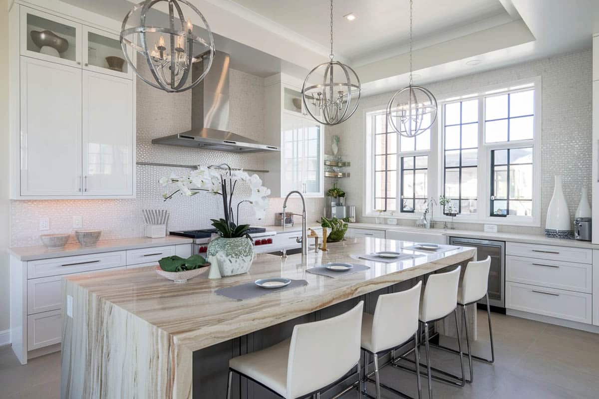 Kitchen with recessed panel cabinets with beige quartz countertop and globe pendants