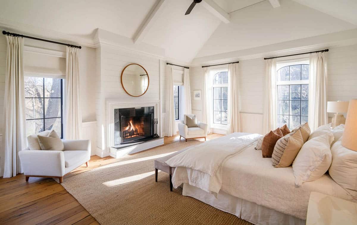 Beautiful white bedroom with paneled wall fireplace and wood board flooring