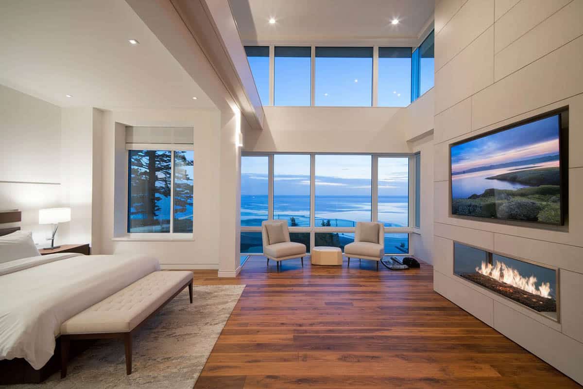 Contemporary crafted bedroom with linear fireplace and water view