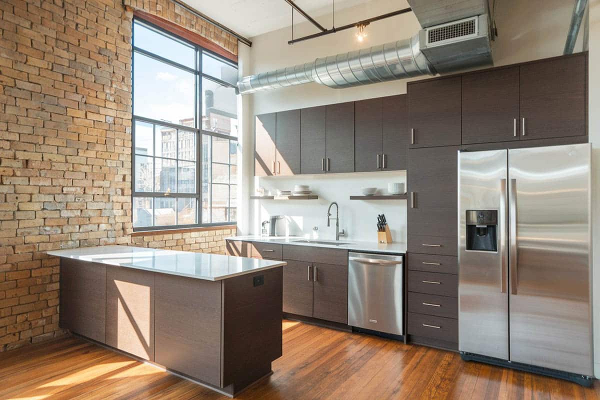 Kitchen with dark brown cabinets, white quartz counters and exposed brick walls