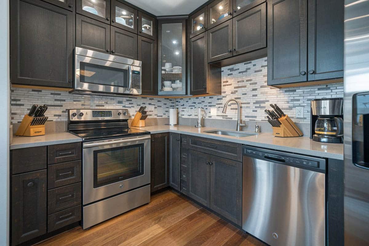 Kitchen with black kitchen cabinets with lighting inside and matchstick mosaic tiles for the backsplash