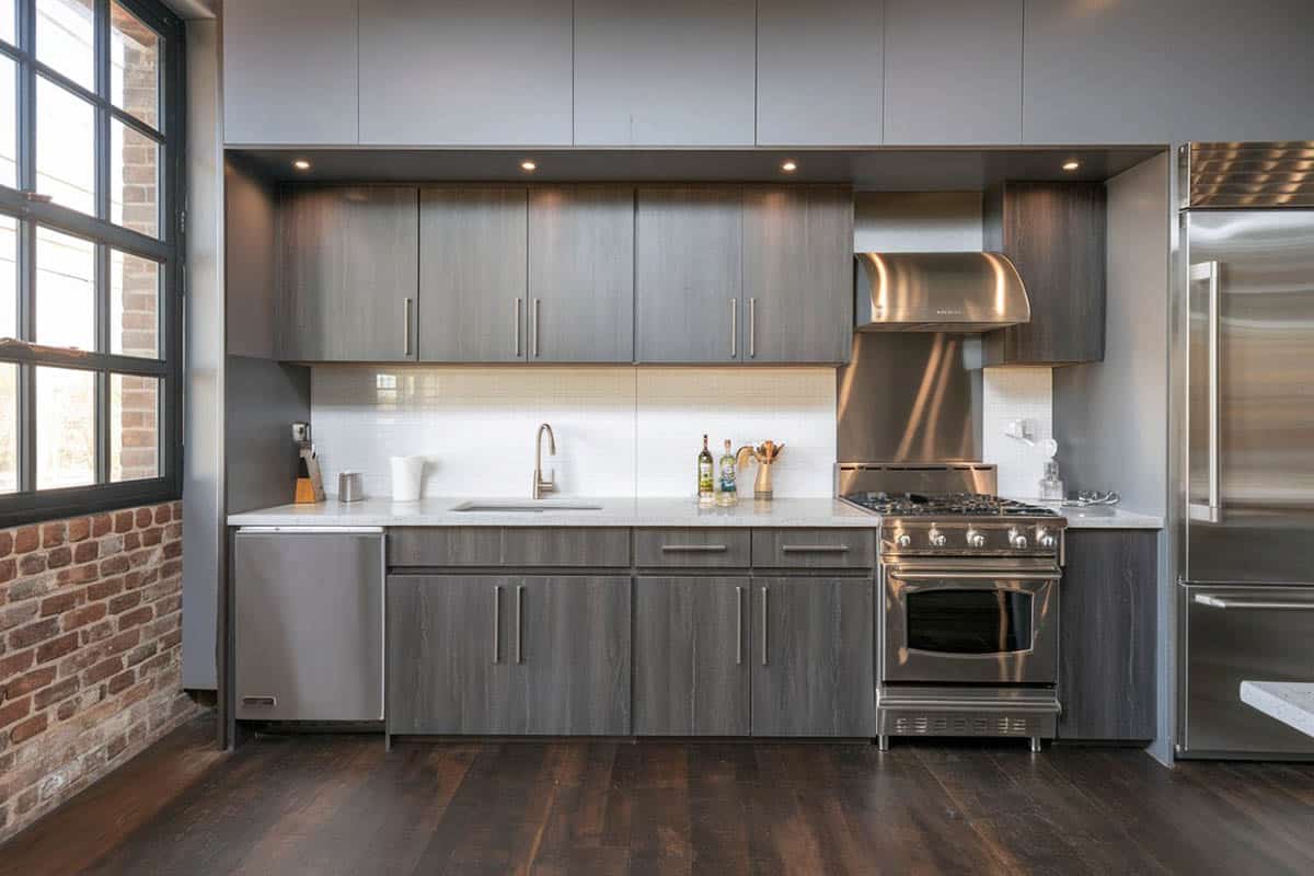 Small one line kitchen with brick wall and white backsplash