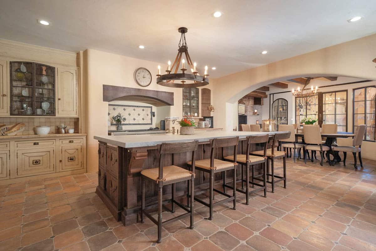Spanish style kitchen with off white base cabinets dark island terracotta floors