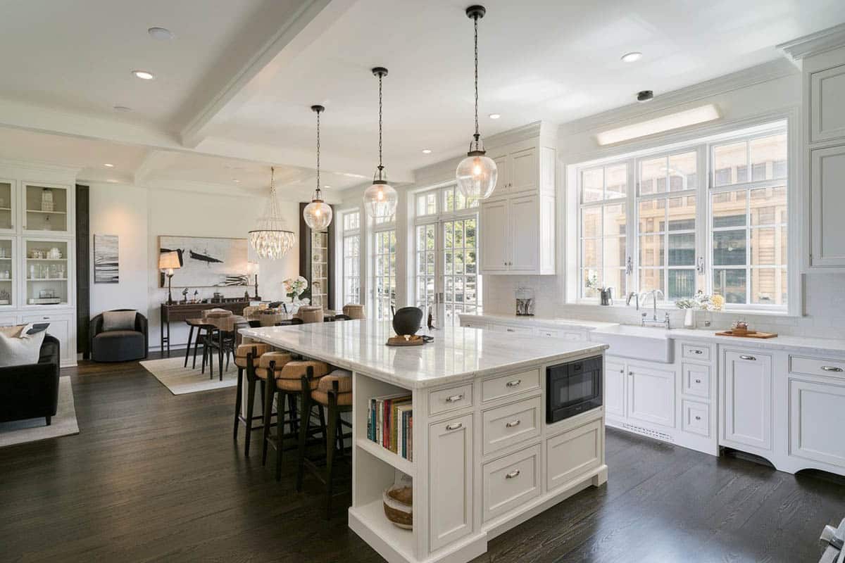 White toned kitchen and dining island open to living room