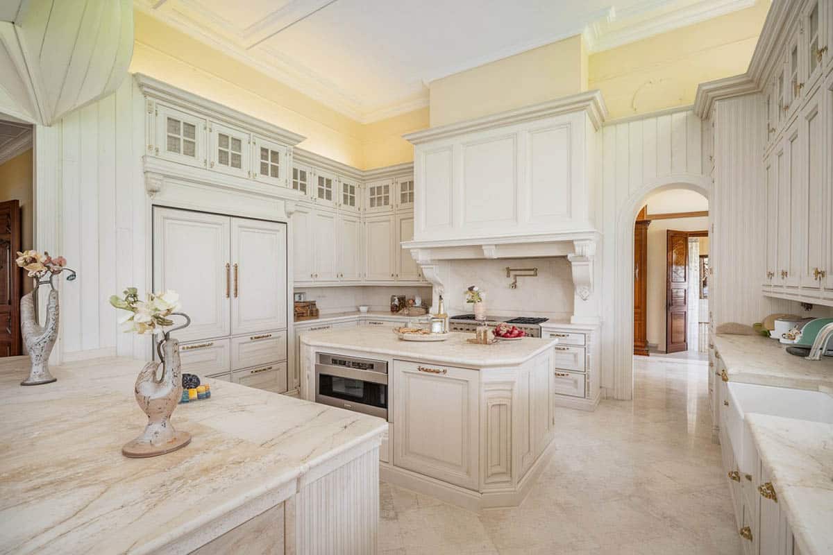 Luxury country kitchen with white cabinetry and white venatino marble countertops with island and peninsula