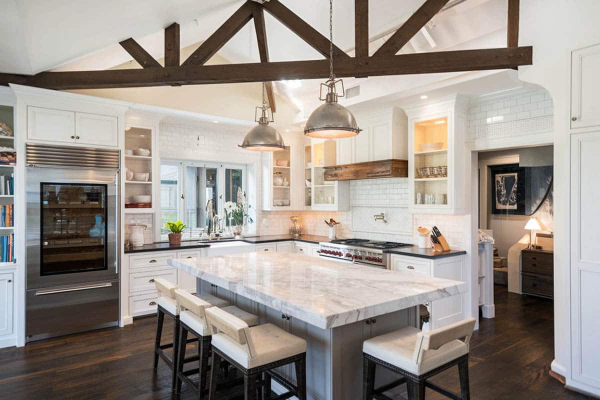 Kitchen with gray island and marble counters, exposed trusses and butlers pantry