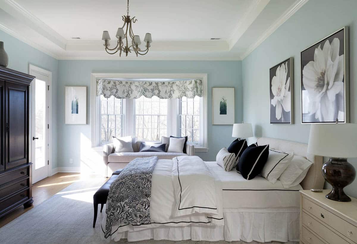 Blue bedroom with white tray ceiling, hanging chandelier and artwork