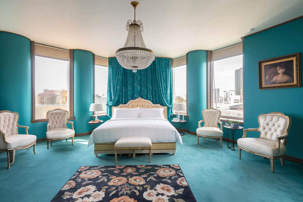 Bedroom with teal painted walls, chandelier and green carpet