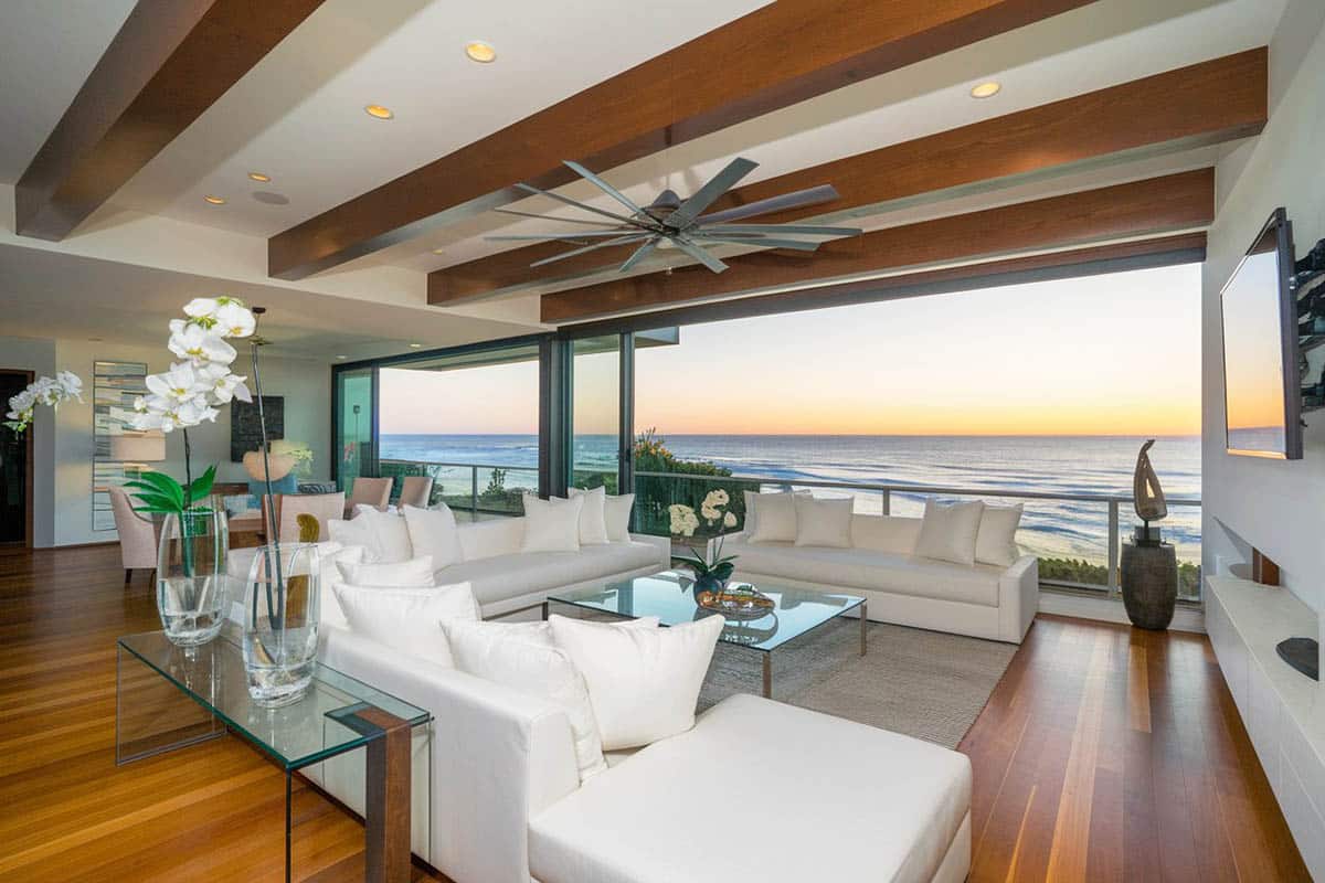 Ocean view contemporary living room with sliding glass doors wood flooring and beam ceiling