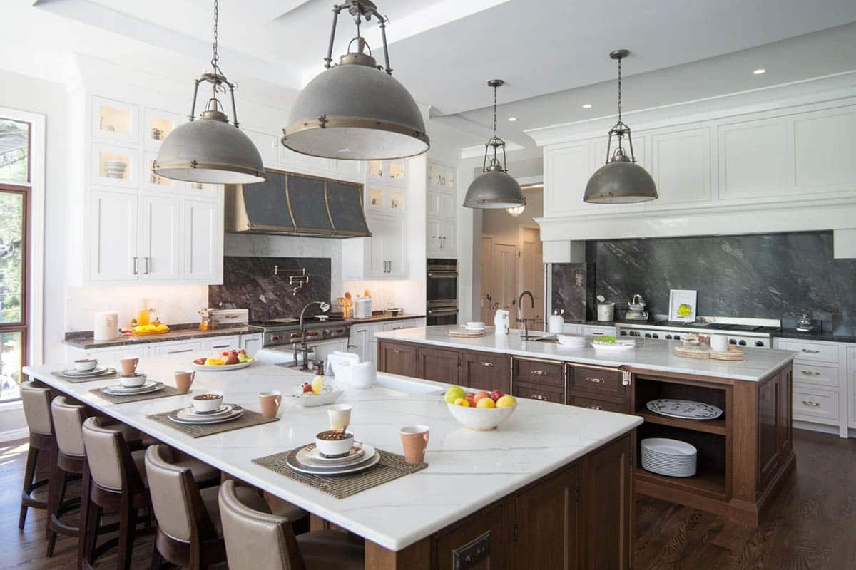 Luxury kitchen with open floor plan design, two islands, marble countertops, white cabinets and chrome pendant lights