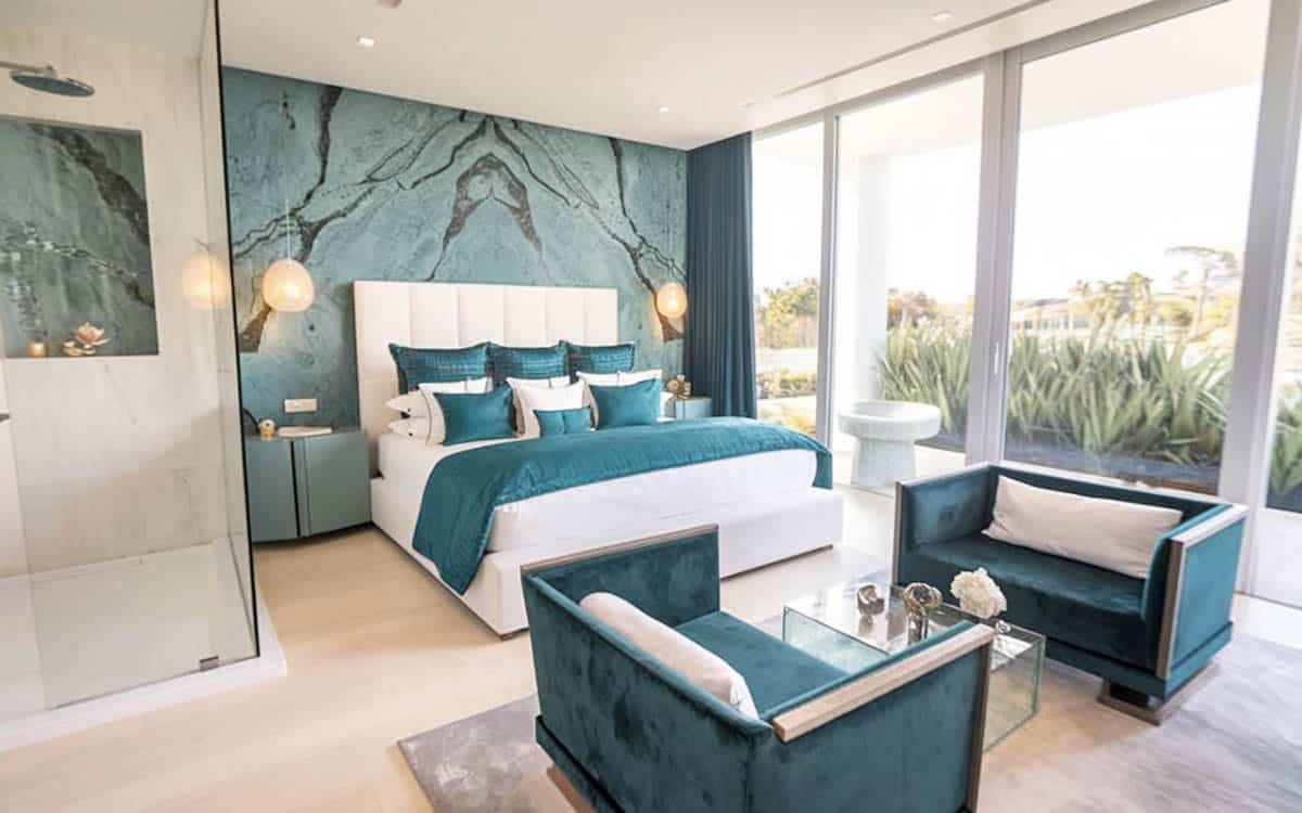 Teal hued bedroom with accent wall sitting area furniture and balcony