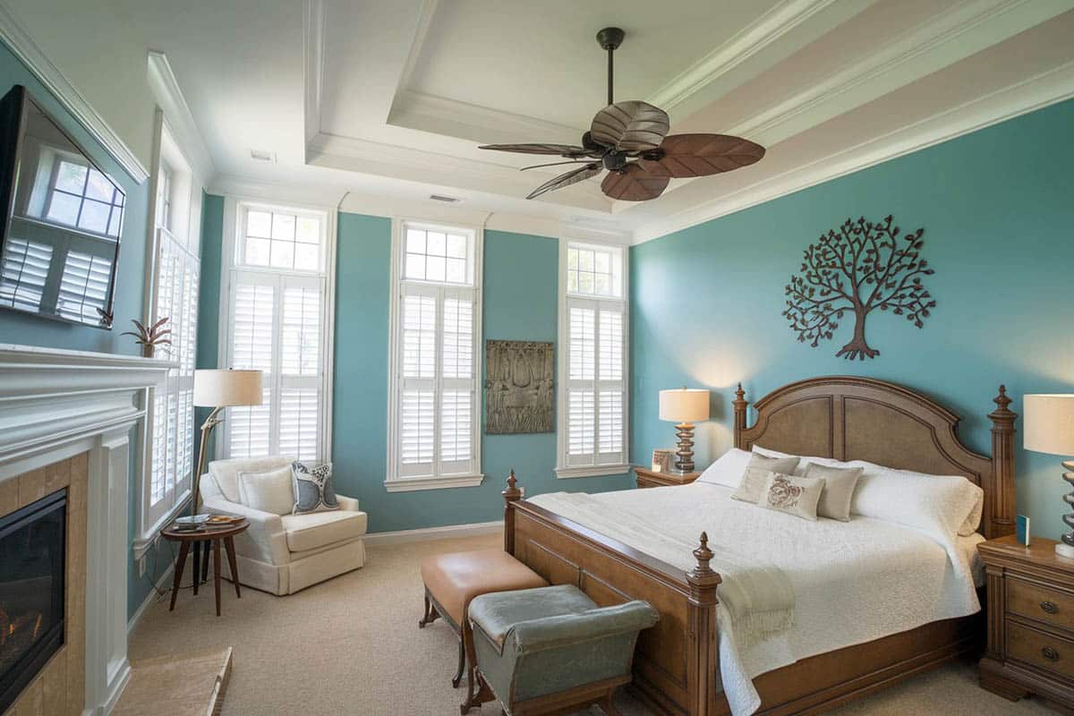 Traditional bedroom with shutters, teal cove ceiling and walls, wood flooring and white molding