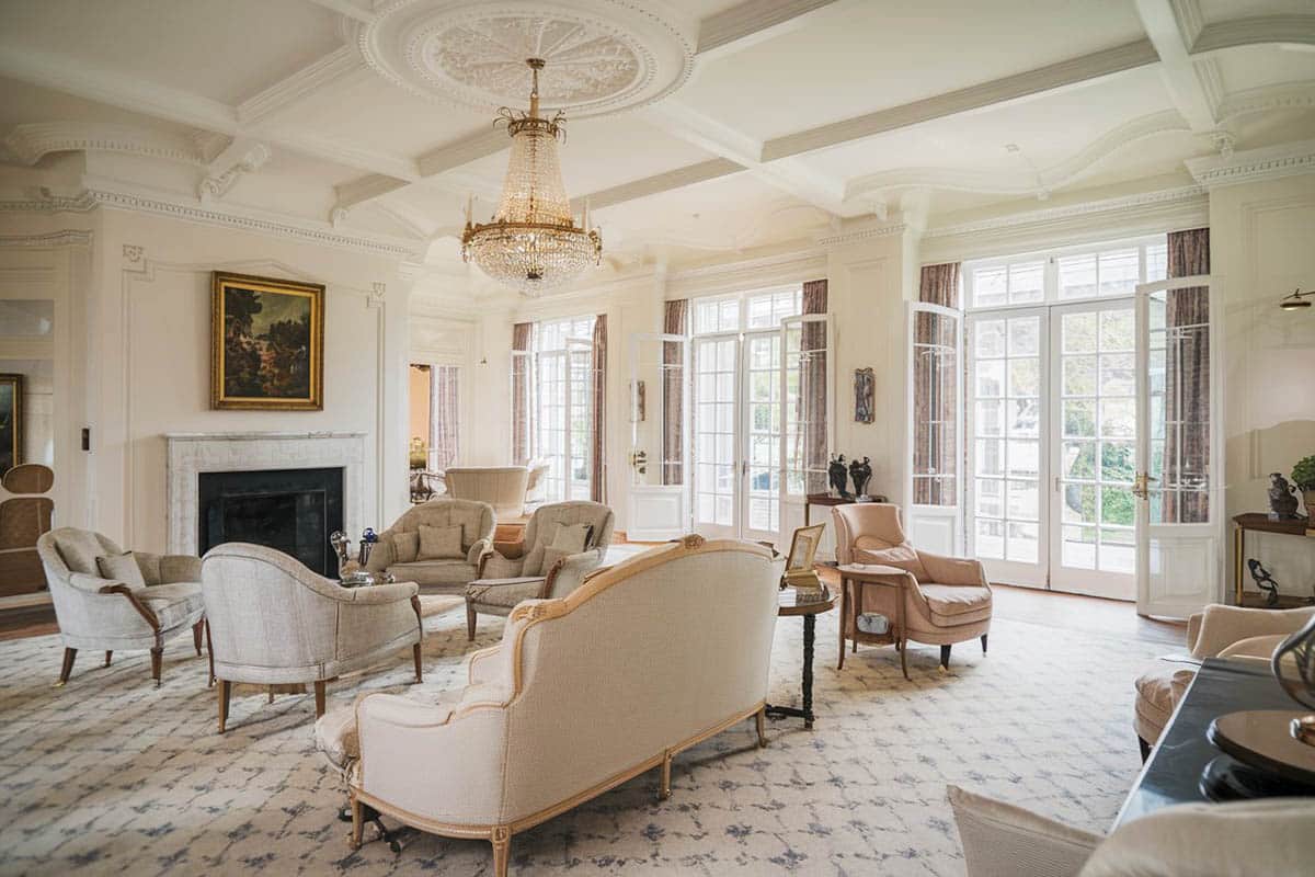 Luxury living area with hampton design fireplace, chandelier and antique armchairs