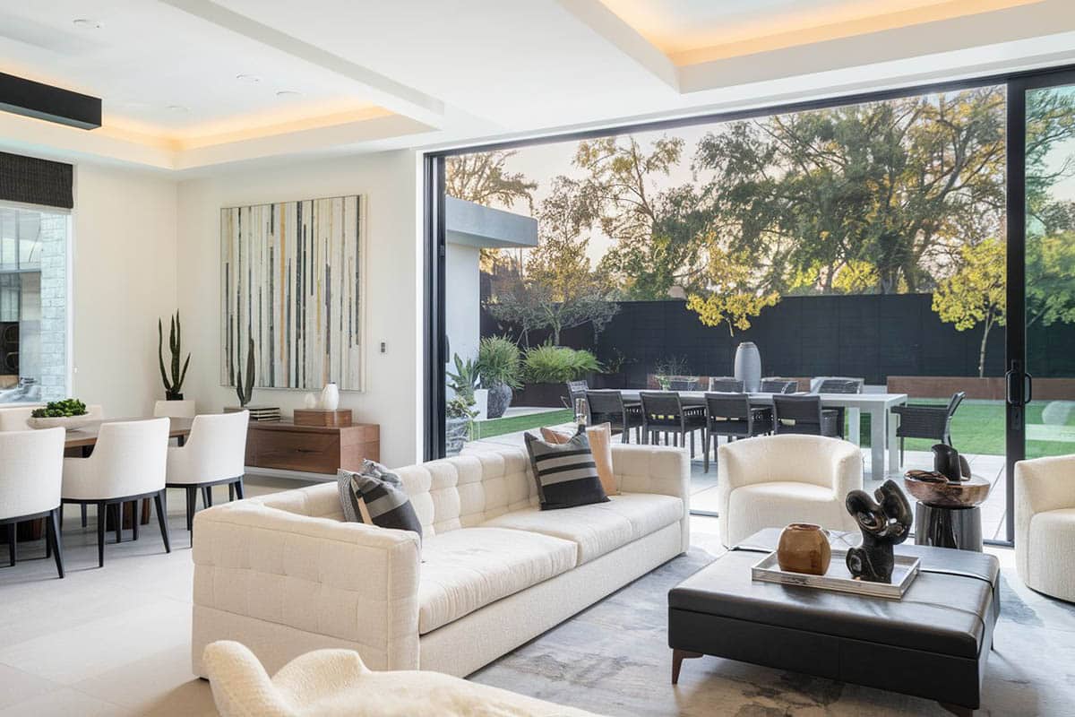 White decorated great room with white sectional couch and outdoor living patio and dining