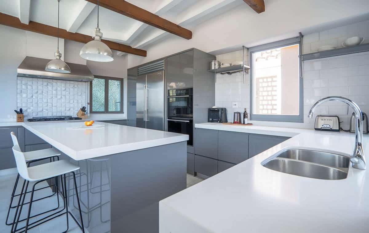 Contemporary kitchen with gray cabinets, white countertops, metallic backsplash and exposed wood beams
