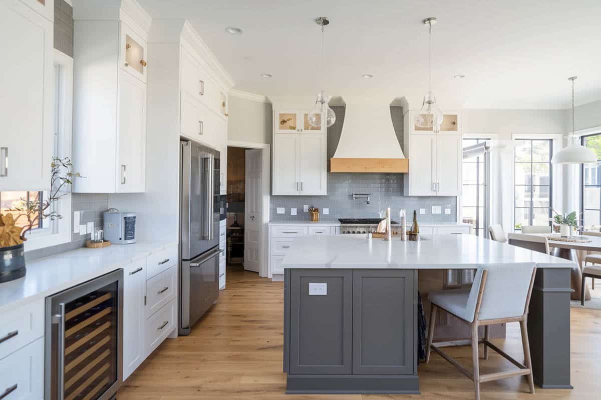Kitchen with white cabinets, dark gray island marble countertops and glass subway tile