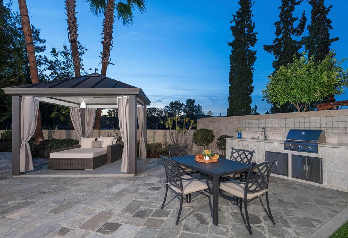 Pavilion with outdoor kitchen, bar area and daybed on stone surface