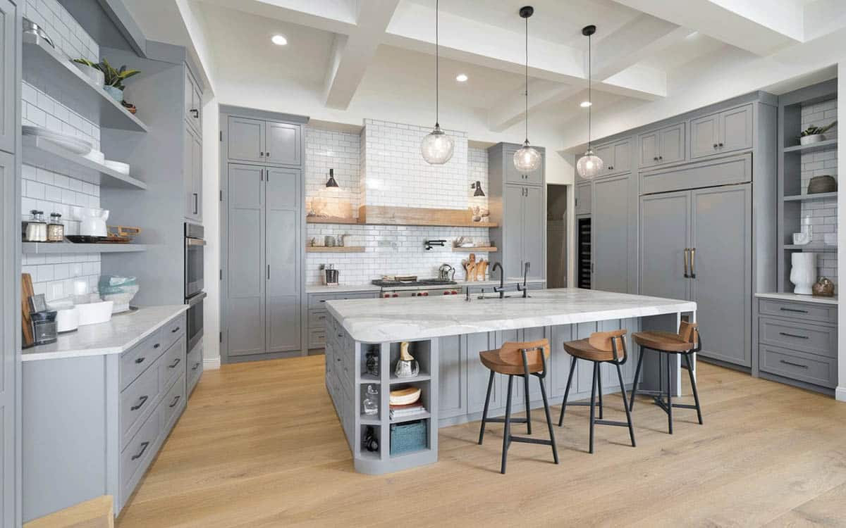 Contemporary light gray kitchen cabinets, light wood floors and white textured backsplash