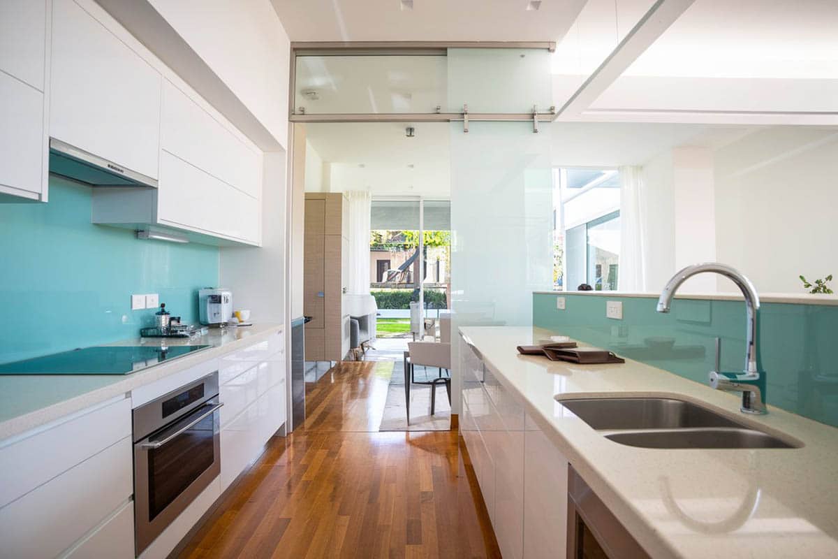 White modern galley kitchen with glass aqua backsplash