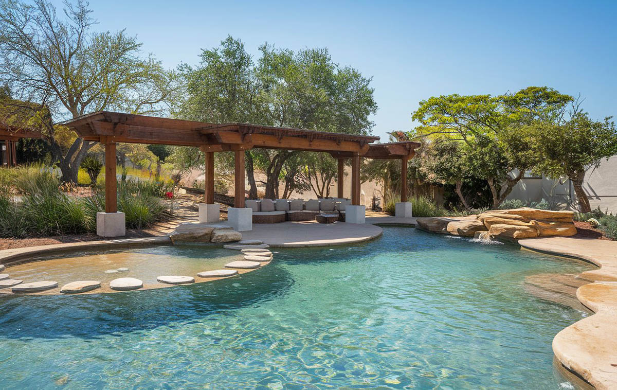 Pool with rock features and a long hallway-like pergola