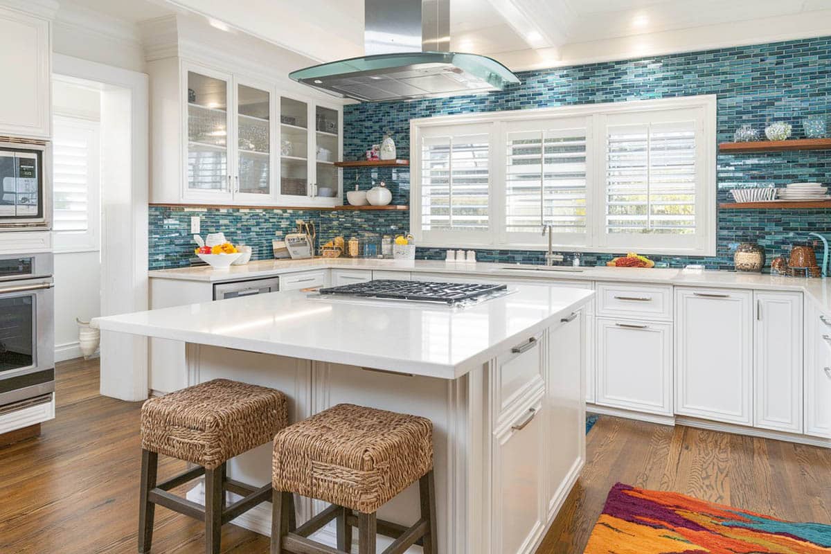 Kitchen with unique blue glass wall backsplash, stools with fabric upholstery and skylight