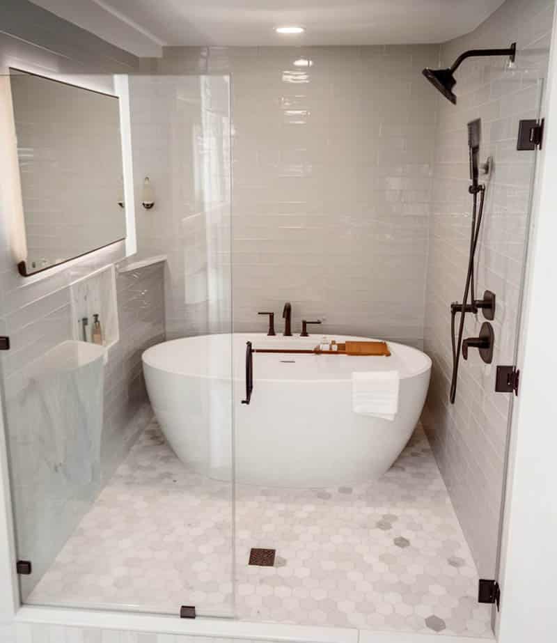 Wet room shower with oval tub and bronze hardware