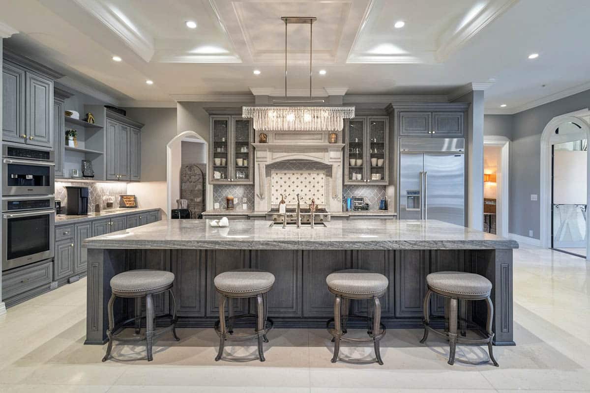 Custom wood island in luxury home with gunmetal color cabinets and linear chandelier