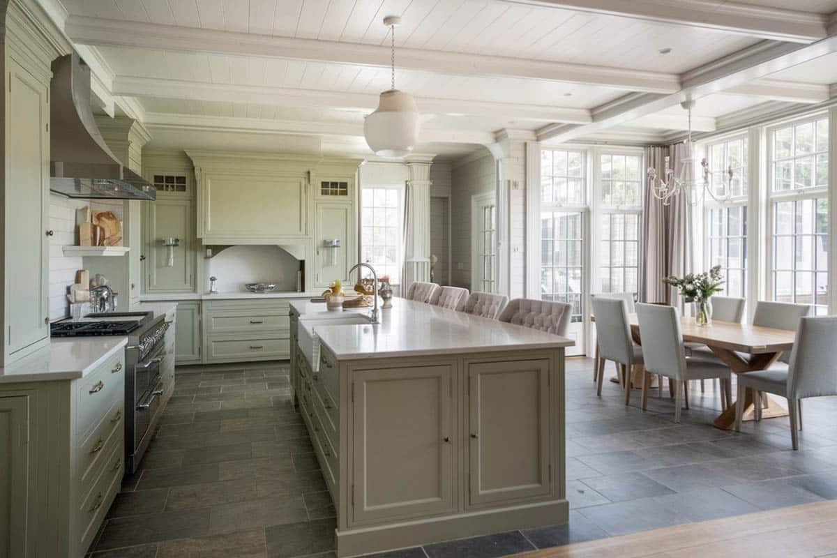 Decorative island with marble counter with green cabinets and tufted seats