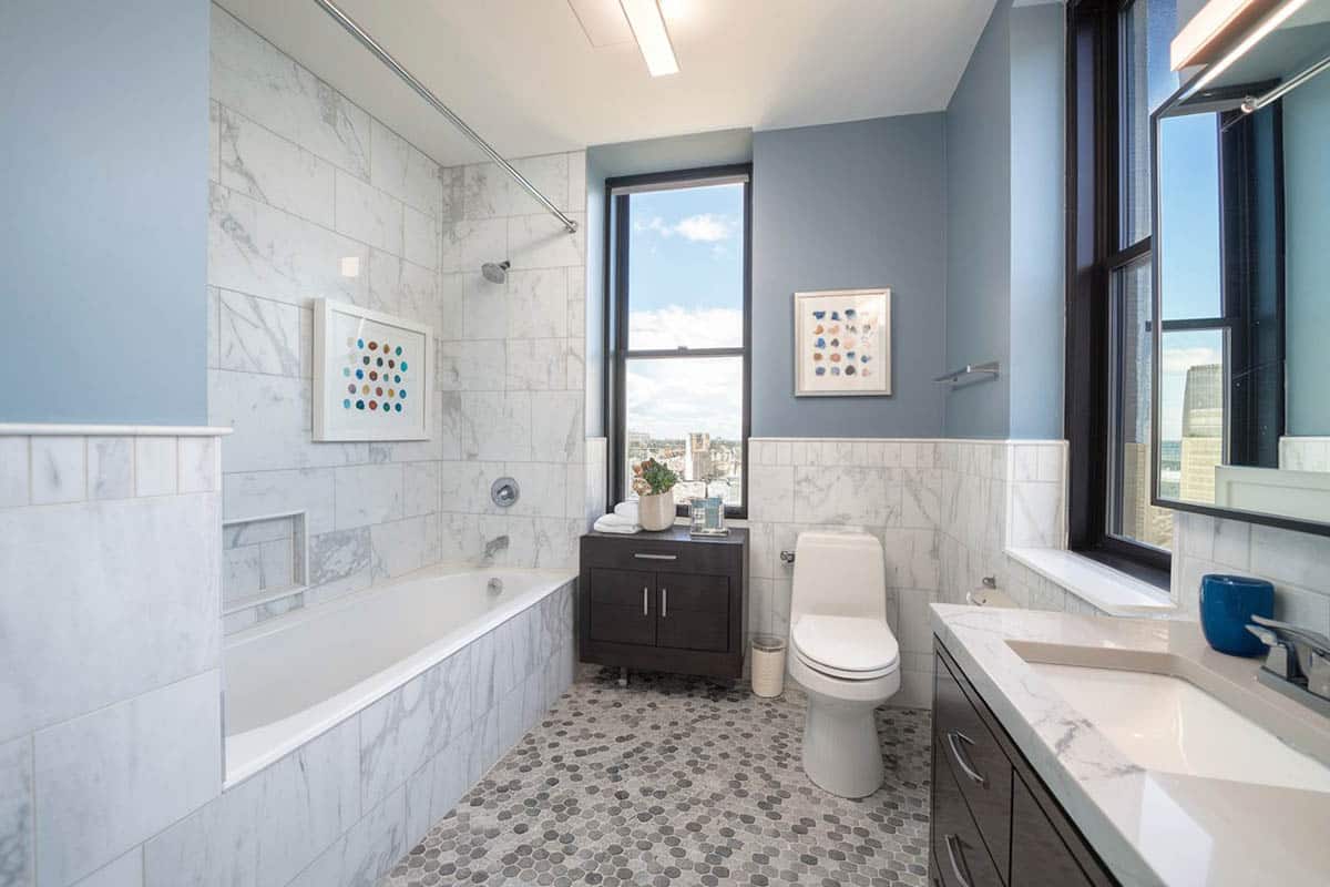 Bathroom with light blue paint and penny tiles in gray