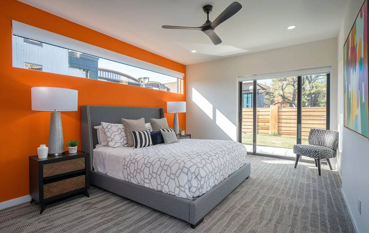 Contemporary bedroom with orange wall and gray carpet