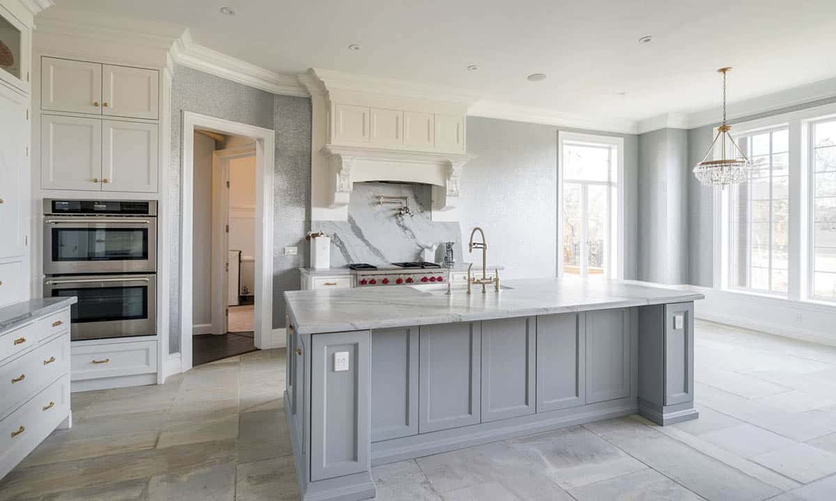 Kitchen with white cabinets, gray island, light gray wall paint and flooring.
