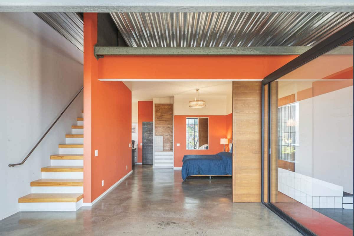 Loft bedroom with orange painted wall and gray finished concrete surface floors