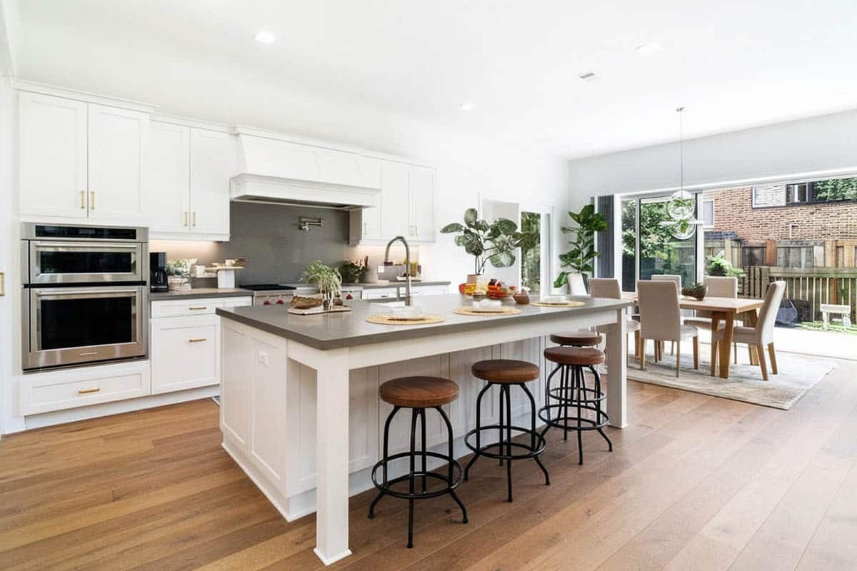 Contemporary kitchen with gray silestone countertops dining island white cabinets wood flooring