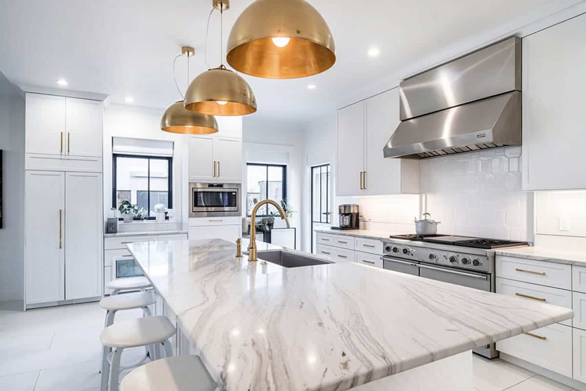 Contemporary kitchen with marble countertop island and gold pendant lights