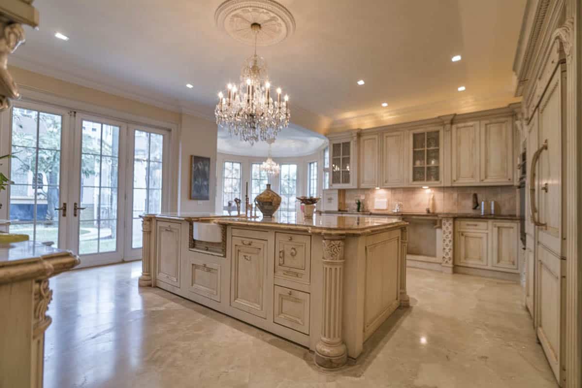 Traditional kitchen with cream cabinets, chandelier and crema marfil marble counter