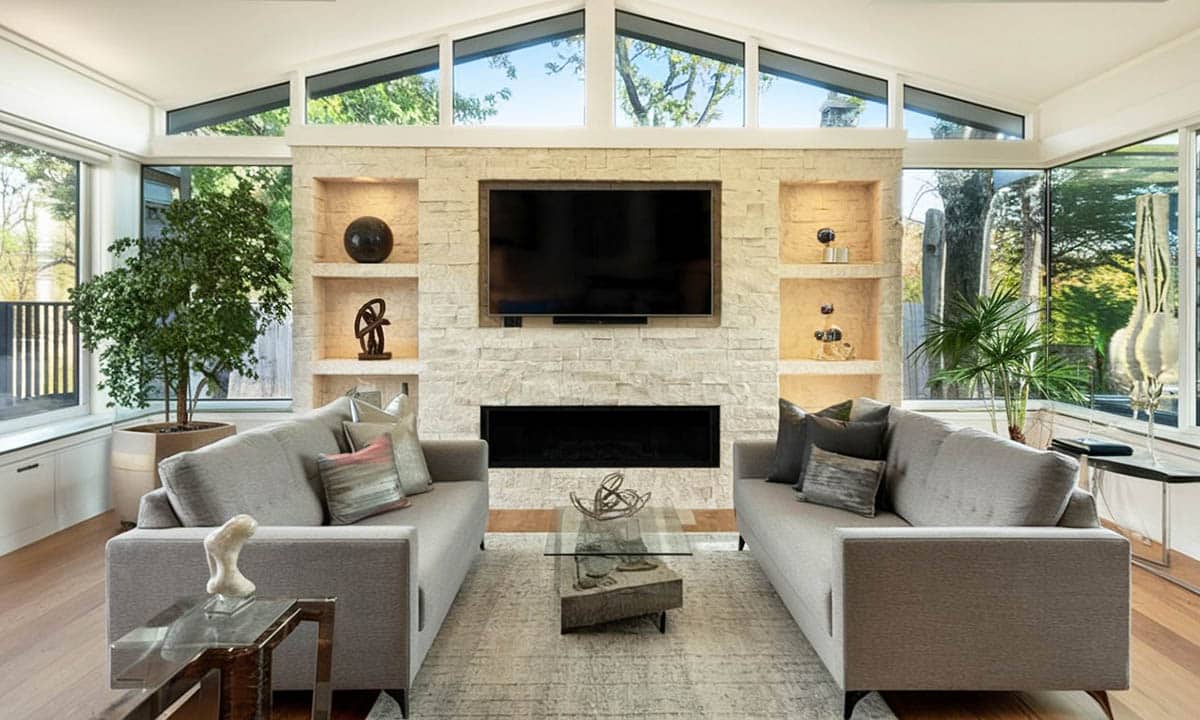Room with stacked stone accent wall with lighting and shelving