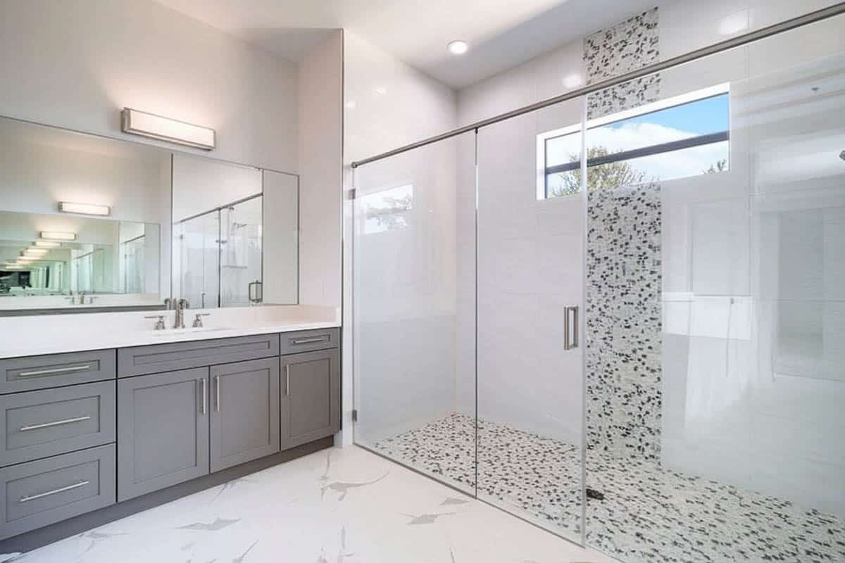 Mosaic pattern tiles on shower floor and walls and white vanity